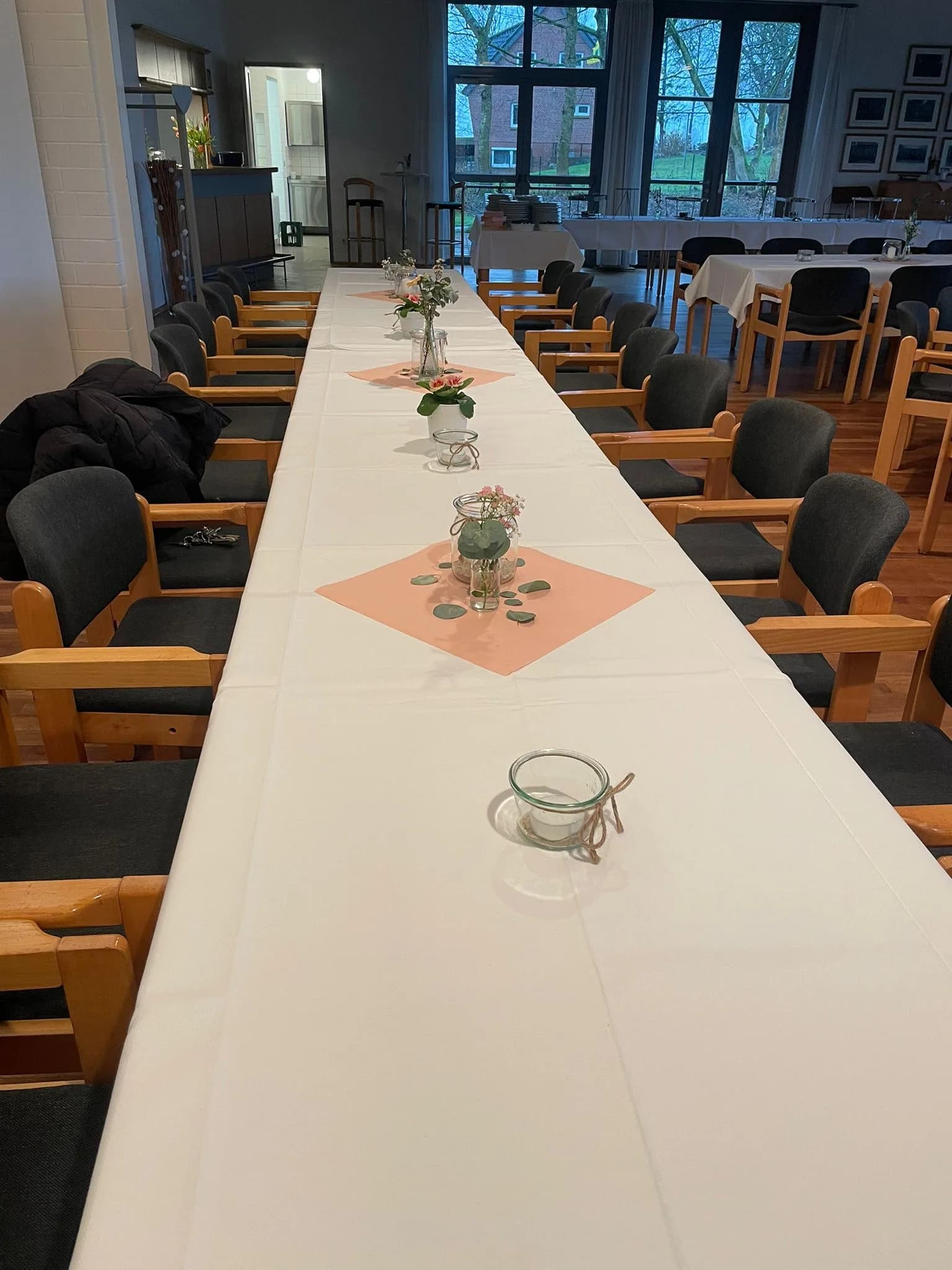 Lange weiße Tafel, die durch den ganzen Raum läuft, mit Läufern in Apricot, kleinen Vasen und Windlichtern