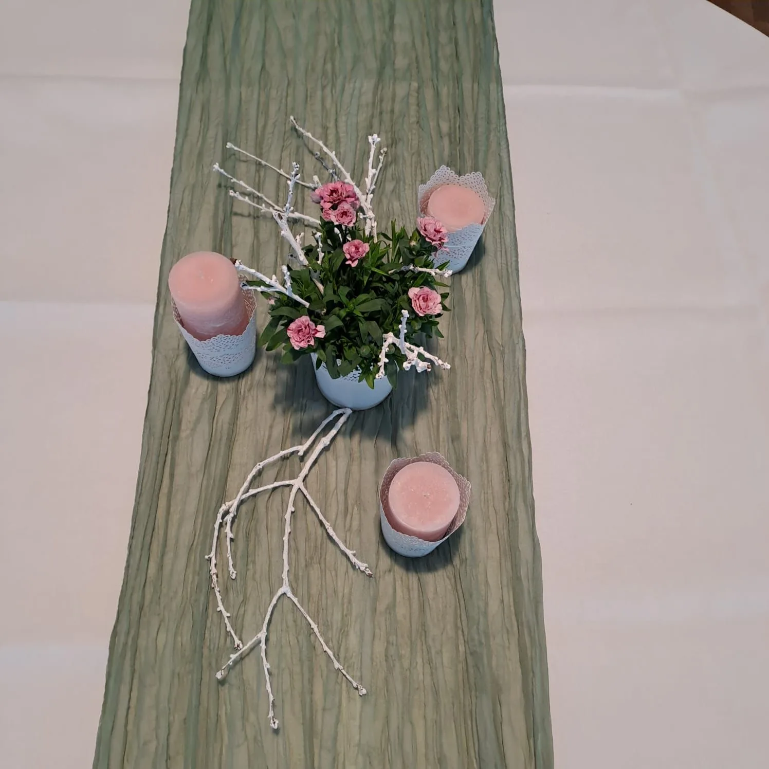 Salbeigrüner Läufer auf weißem Tuch mit rosa Rosen, rosa Kerzen und einem weiß gekalkten Zweig