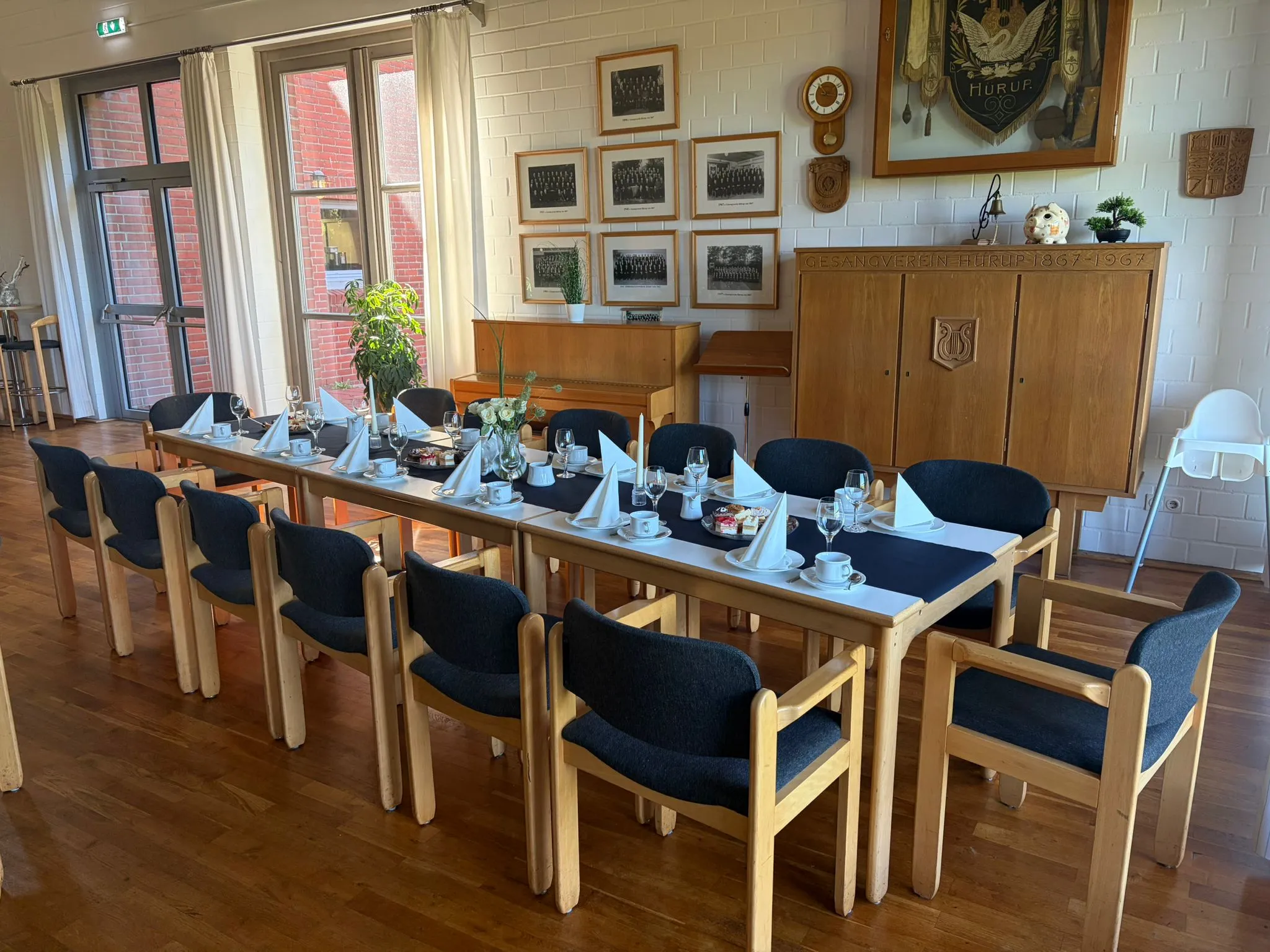 Langer Tisch mit blauen Stühlen vor der Bilderwand und dem Schrank